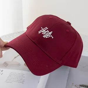 Detail of burgundy baseball cap with white artistic embroidery and reinforced brim stitching