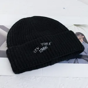 Detail of black wool knit beanie featuring white New York 1986 embroidery text