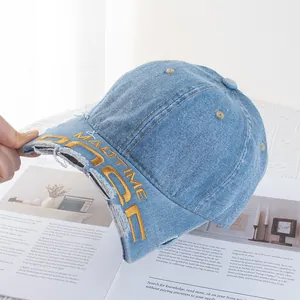 Détail macro du bord en jean effiloché et broderie jaune sur cette casquette vintage