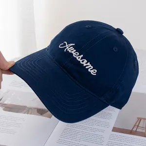 Detail of navy cotton baseball cap with white Awesome embroidery on an open magazine
