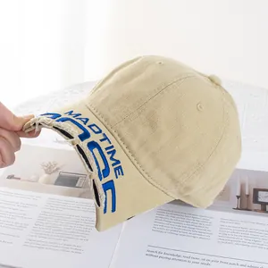 Détail de la broderie bleue MADTIME sur casquette beige vieillie avec bords effilochés