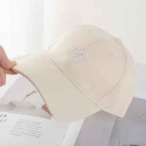Detail shot of beige cotton baseball cap with artistic white embroidery and wide brim