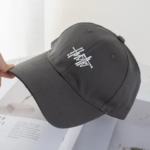 Detailed view of dark grey cotton baseball cap featuring white artistic letter embroidery