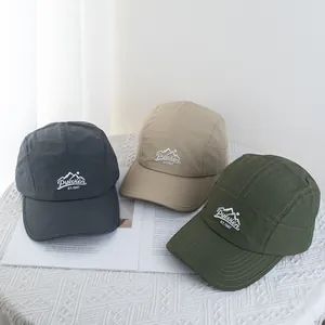 Outdoor camper hats in multiple colors featuring mountain embroidery on a textured table