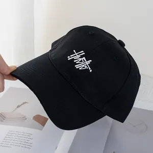 Close-up of black cotton baseball cap with white letter embroidery and curved brim