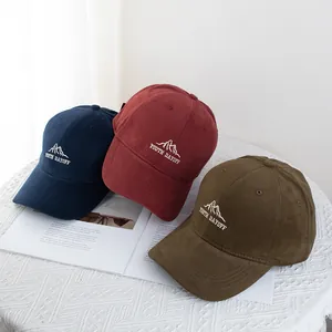 Three embroidered cotton baseball caps in navy, burgundy and olive on a white table