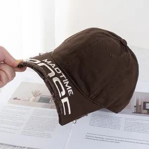 Gros plan sur la casquette vintage marron avec broderie MADTIME et bords effilochés