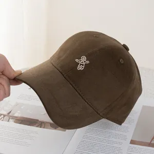 Detailed view of white astronaut embroidery on a dark brown cotton canvas baseball cap