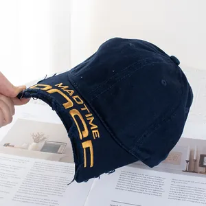 Détail de la casquette de baseball en denim bleu foncé avec broderie jaune et visière usée