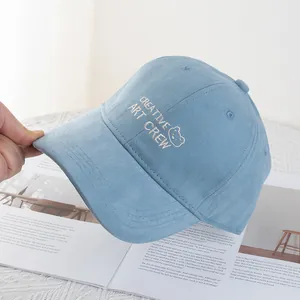 Close-up of light blue baseball cap featuring bear embroidery and creative art crew text