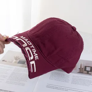 Gros plan sur la broderie MADTIME et la visière usée de la casquette bordeaux