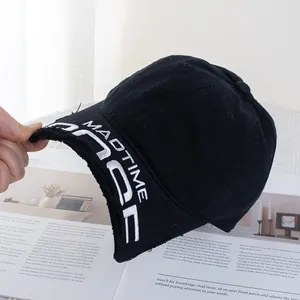 Gros plan du bord usé avec bords effilochés et broderie blanche sur une casquette noire