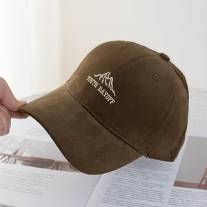 Detail of dark brown corduroy baseball cap featuring white mountain embroidery and youth text