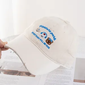Detail of cream baseball cap featuring cartoon animal embroidery and frayed brim edge