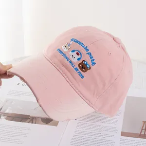 Close-up of pink baseball cap featuring cartoon animal embroidery and distressed brim