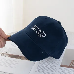 Close-up of navy blue cotton baseball cap with white bear embroidery on an open magazine