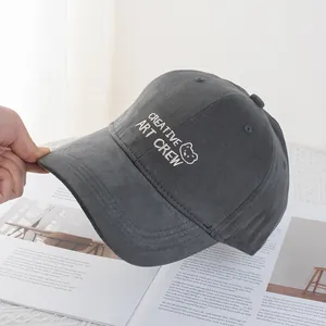 Detail of dark grey corduroy baseball cap with white bear embroidery on fabric