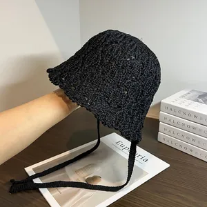 Vista dettagliata del cappello a secchiello in paglia nera lavorata a mano con lacci