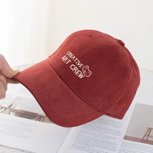 Close-up of burgundy cotton baseball cap with white bear embroidery and creative art crew text