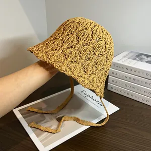 Dettaglio del cappello in paglia giallo zenzero con trama traforata e nastri