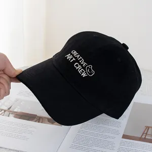 Detail of black cotton baseball cap with white bear embroidery and creative art crew text