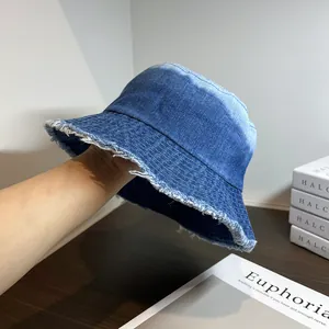 Détail montrant le bord effiloché et la texture du denim bleu vintage du bob en jean