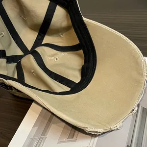 Detail of khaki vintage baseball cap with distressed brim and embroidered lettering