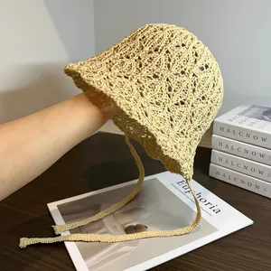 Dettaglio del cappello di paglia beige fatto a mano con nastri decorativi e lacci