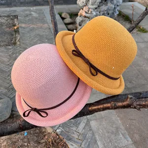 Breathable woven cloche hats in pink and yellow with ribbon bows on tree branch