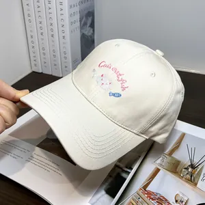 Dettaglio del ricamo a gatto e della scritta 'Cats eat fish' su un cappellino di cotone beige