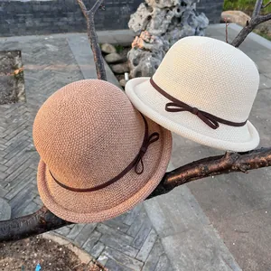Detail of knit sun hat with brown ribbon bow hanging on tree branch outdoor