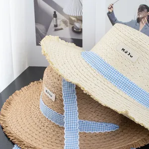 Elegant wide brim straw sun hat with fringe edge and gingham ribbon for beach vacation