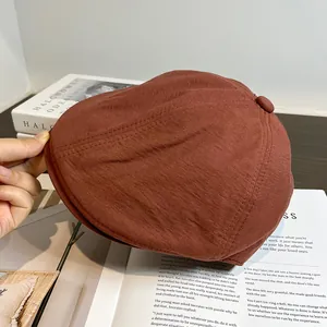 Gros plan détaillé de la casquette gavroche terracotta avec bouton et coutures texturées