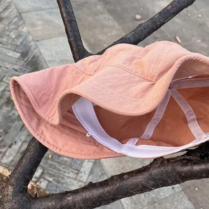 Detail of pink nylon bucket hat featuring white sweatband and adjustable drawstring