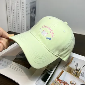 Dettaglio ravvicinato di cappello in cotone verde con ricamo di gatto e pesce