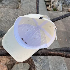 Detailed interior of a beige cotton baseball cap with embroidery on a tree branch