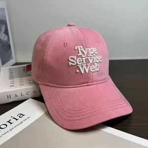 Close-up of pink cotton baseball cap with white 3D embroidery on a wooden table
