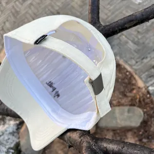 Detail of off-white baseball cap interior with sweatband, adjustable strap, and logo tag