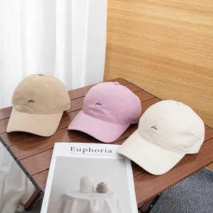 Drie geborduurde katoenen baseballcaps in kaki roze en beige op een houten tafel