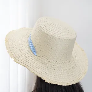 Close-up of wide-brimmed straw hat with frayed edges and blue checkered ribbon detail