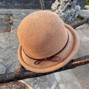 Detailed close-up of straw sun hat featuring a delicate bow and elegant curled brim texture