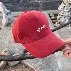 Close-up of deep red baseball cap featuring white my putt embroidery on cotton fabric