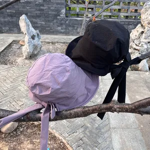Outdoor view of lightweight sun hats with ribbon bows in purple and black finishes