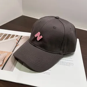 Primer plano de gorra de algodón gris con bordado N rosa sobre una revista abierta