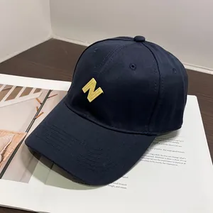 Detalle de gorra de béisbol de algodón azul marino con bordado N amarillo sobre revista