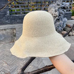 Makro-Detail von beigem Sonnenhut mit feiner Stricktextur und gewellter Krempe