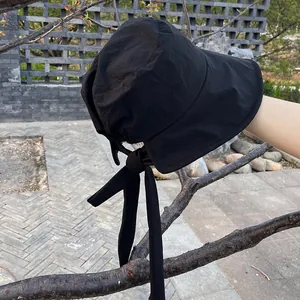 Detail showing the ribbon bow and texture of the lightweight black sun hat with wide brim