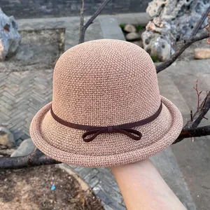 Detailed close-up of straw sun hat featuring a delicate bow tie and rolled edge brim