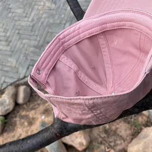 Detail view of pink cotton baseball cap interior showing stitching and metal buckle