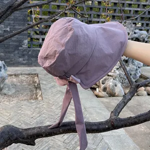 Detail of purple sun hat with ribbon bow and long streamers on tree branch